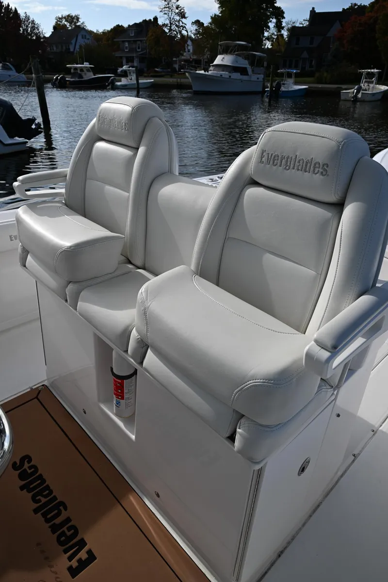 Slide: The Image of 2019 Everglades 295 Center Console boat with white leather seats at a marina. - 36