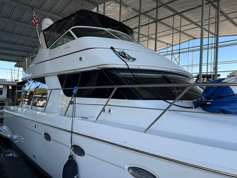 The Image of 2001 Carver 450 Voyager Pilothouse yacht docked under a covered marina. - 0