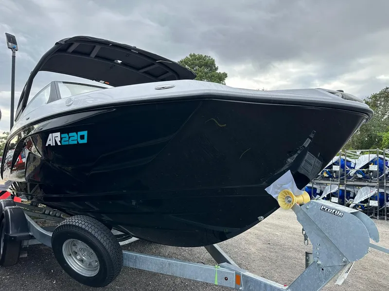 Slide: The Image of 2025 Yamaha Boats AR220 on trailer, sleek black design, parked outdoors. - 2