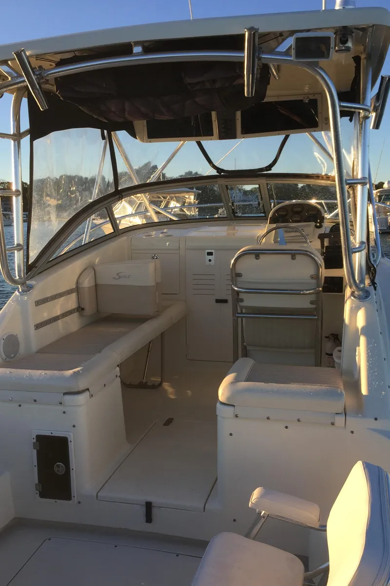 Slide: The Image of 2004 Scout 280 Abaco boat interior with seating and helm, docked at sunset. - 8