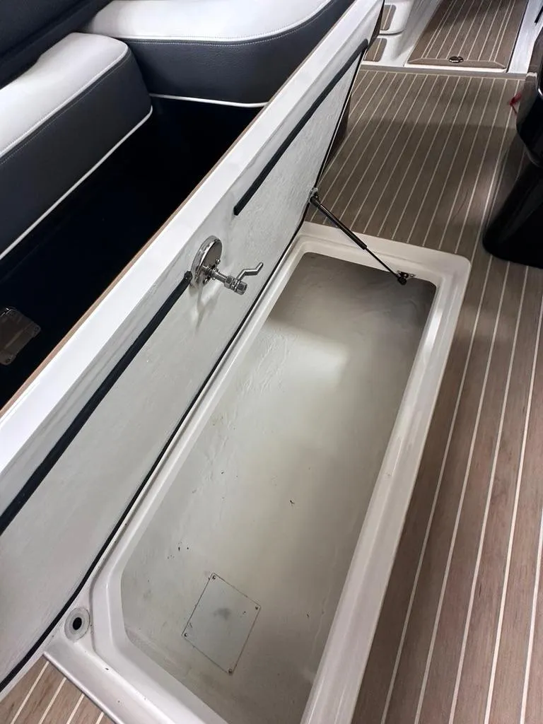 Slide: The Image of 2015 Regal 2800 Bowrider storage compartment with open lid on wooden deck. - 5