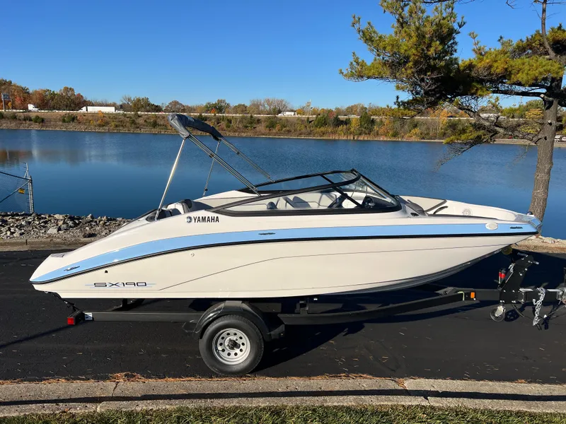 Slide: The Image of 2025 Yamaha Boats SX190 on trailer by a serene lake. - 4