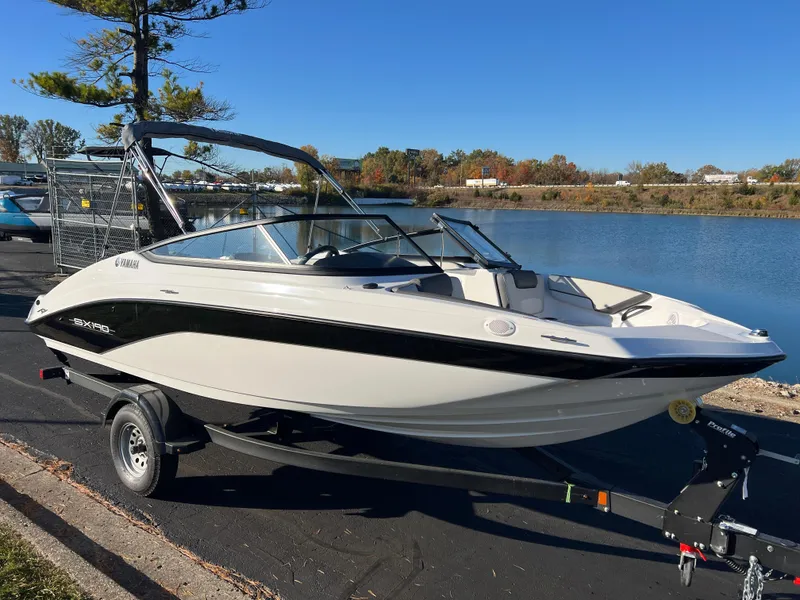 Slide: The Image of 2025 Yamaha Boats SX190 on trailer by a lake, under clear blue sky. - 3