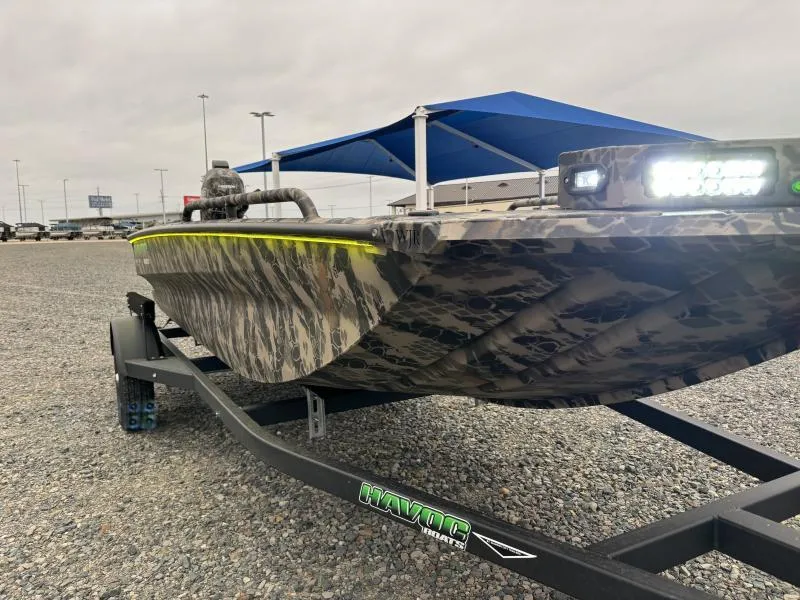 Slide: The Image of 2024 Havoc Boats 1653 MSTC with camouflage design on a trailer, under a blue canopy. - 3