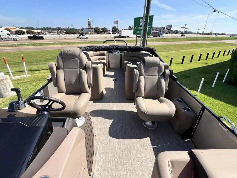 Slide: The Image of 2024 Veranda VTX25RC pontoon boat with plush seating, parked near a highway. - 10