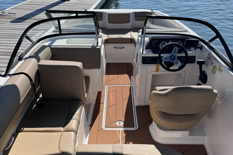 Slide: The Image of 2023 Bayliner DX2000 boat interior with seating and steering wheel, docked by the water. - 4