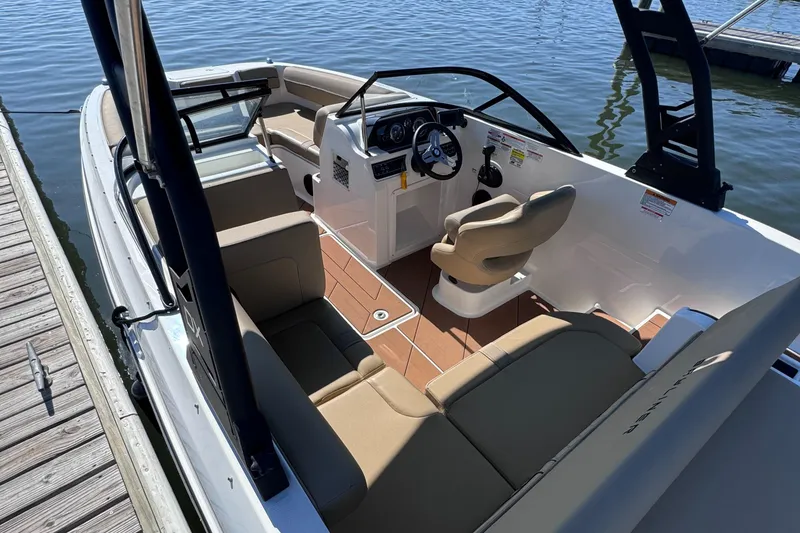 Slide: The Image of 2023 Bayliner DX2000 boat interior with seating and steering wheel, docked by the water. - 6