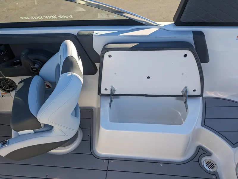 Slide: The Image of 2025 Chaparral 247 SSX boat interior with open storage compartment and captain's chair. - 15
