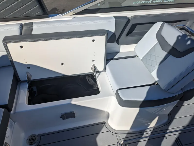 Slide: The Image of 2025 Chaparral 247 SSX boat interior with open storage compartment and cushioned seating. - 28