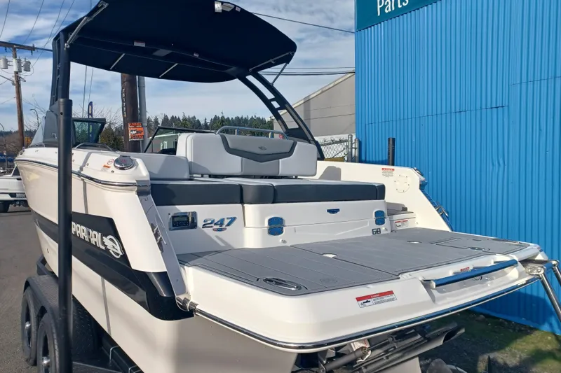 Slide: The Image of 2025 Chaparral 247 SSX boat, rear view, parked on a trailer near a blue building. - 9