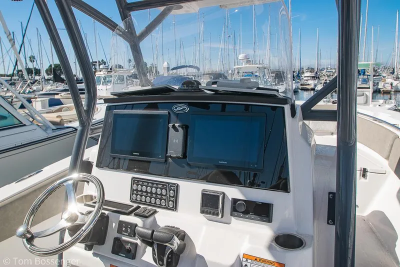 Slide: The Image of 2022 Sea Fox 288 Commander boat dashboard with dual screens and steering wheel in marina. - 8