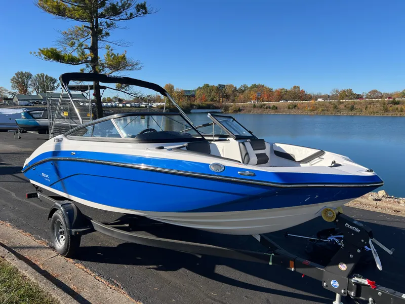 Slide: The Image of 2025 Yamaha Boats SX195, blue and white, docked by a serene lake. - 3