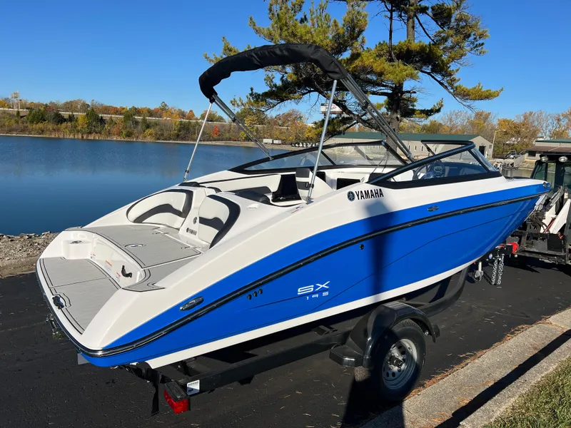 Slide: The Image of 2025 Yamaha Boats SX195, blue and white, docked by a serene lake. - 5