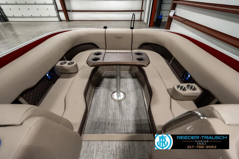 Slide: The Image of 2025 Bennington 25 LTFB boat interior with beige seating and table, in a showroom. - 19