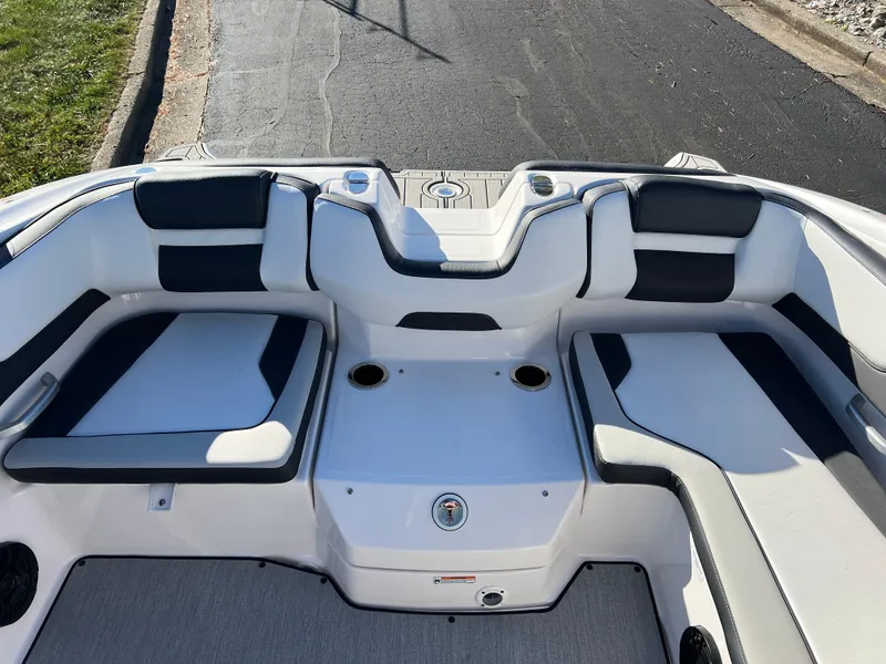 Slide: The Image of 2025 Yamaha Boats SX195 interior seating with cup holders, white and black upholstery. - 19