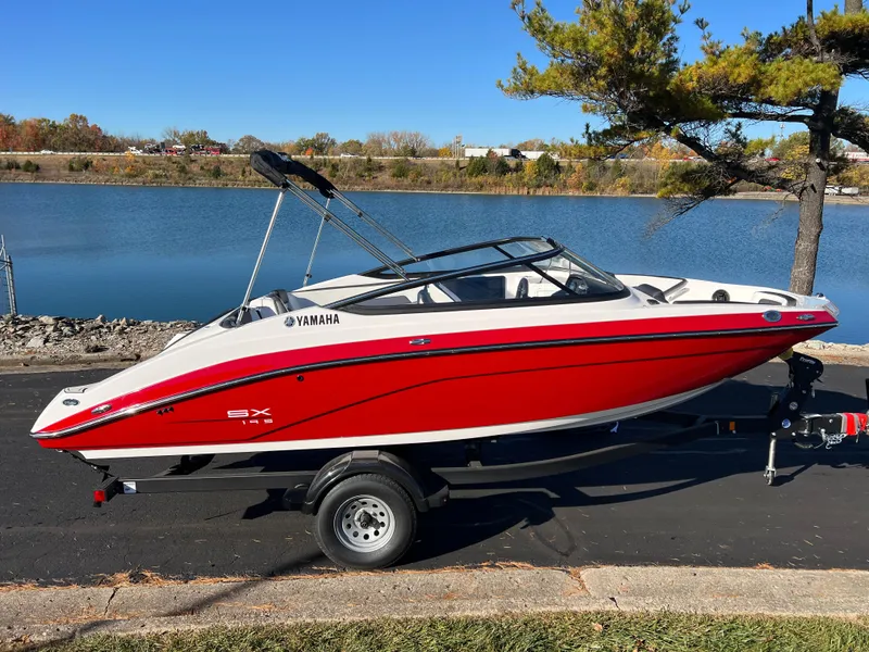 Slide: The Image of 2025 Yamaha SX195 boat, red and white, parked by a serene lake. - 4