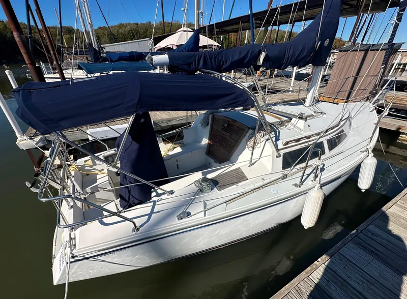 Slide: The Image of 1991 Catalina 28 sailboat docked, featuring blue canvas covers and white hull. - 3