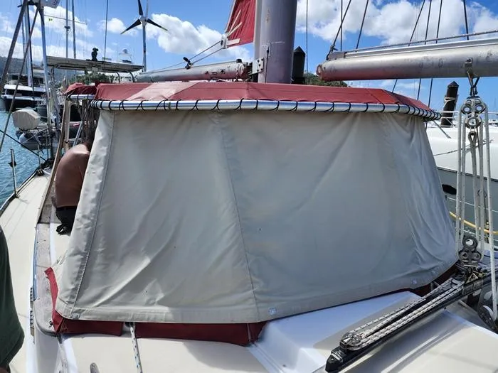 Slide: The Image of 1983 Morgan Schooner with red and beige sail cover, docked at marina under blue sky. - 18
