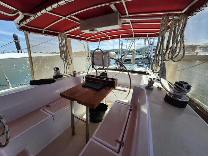 Slide: The Image of 1983 Morgan Schooner cockpit with red canopy, wooden table, and marina view. - 30
