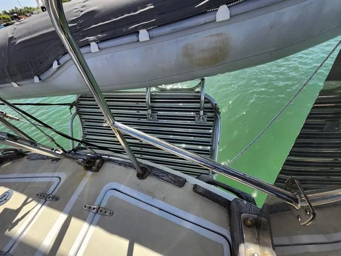 Slide: The Image of 1983 Morgan Schooner deck with dinghy and metal railing over turquoise water. - 32