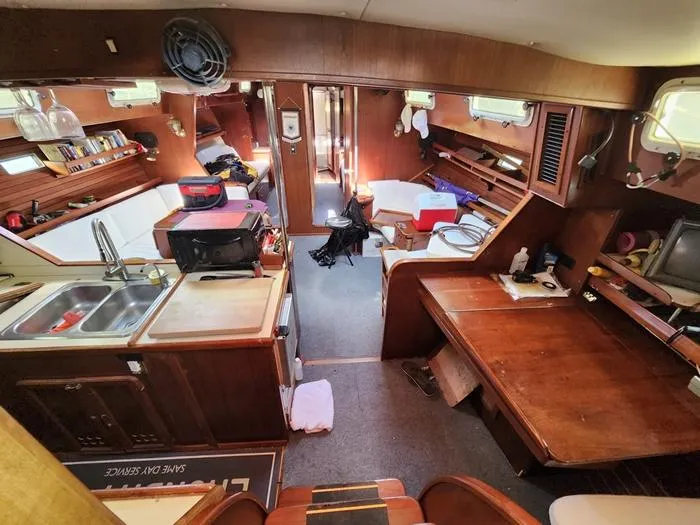 Slide: The Image of 1983 Morgan Schooner interior with wooden furnishings, kitchen, and seating area. Cozy and functional design. - 44