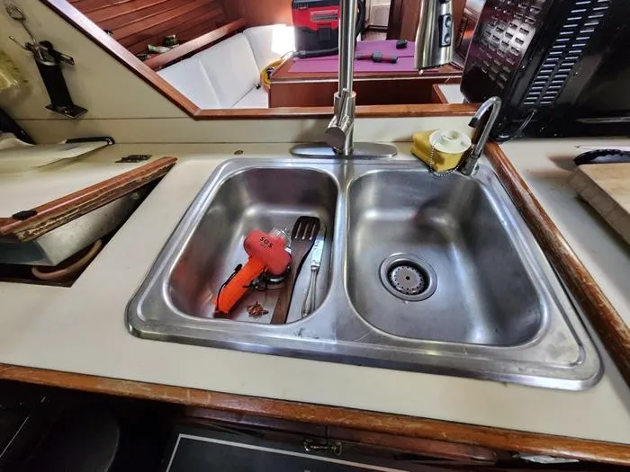 Slide: The Image of 1983 Morgan Schooner kitchen sink with utensils and faucet in a cozy cabin setting. - 48