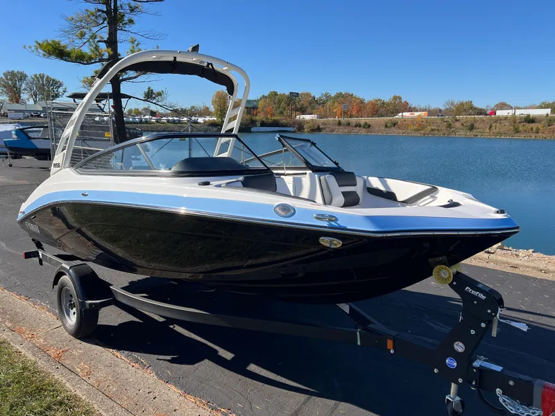 Slide: The Image of 2025 Yamaha Boats 195S on trailer by a lake, sleek black and white design. - 3