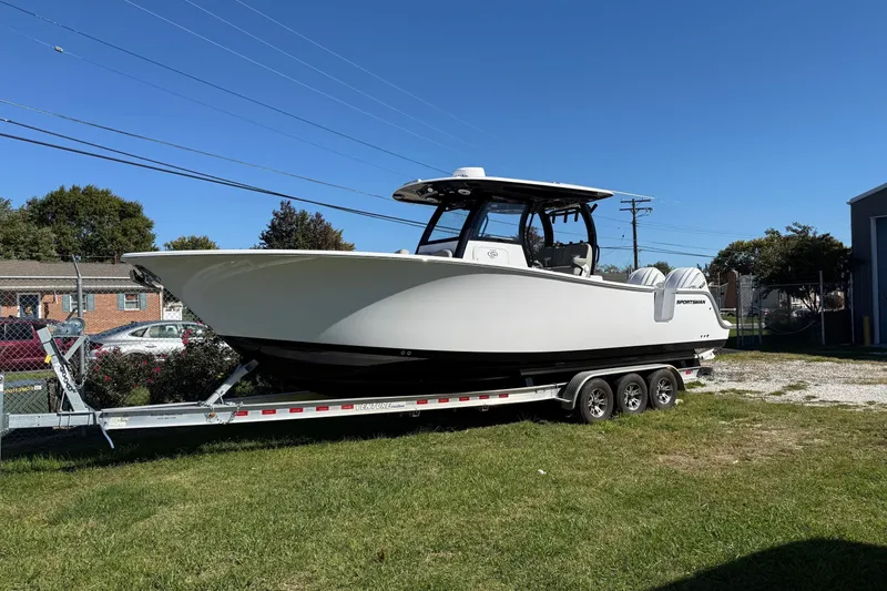 Slide: The Image of 2025 Sportsman Open 302 Center Console boat on trailer, parked on grass under clear blue sky. - 2