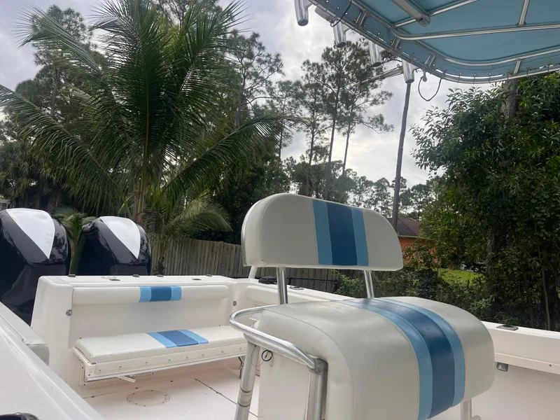 Slide: The Image of 2002 Mako 282 Center Console boat with blue-striped seating, set against a tropical backdrop. - 3