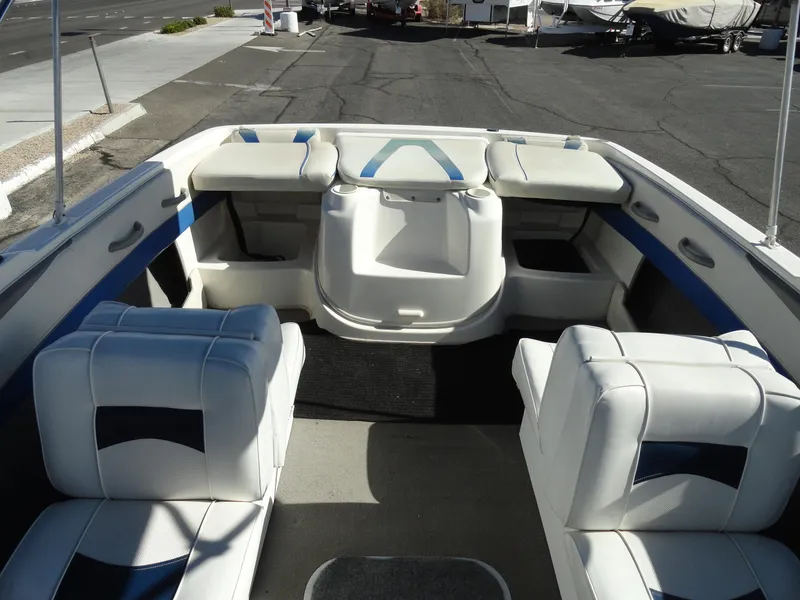 Slide: The Image of 2006 Bayliner 195 Bowrider interior with white and blue seating, parked on pavement. - 14
