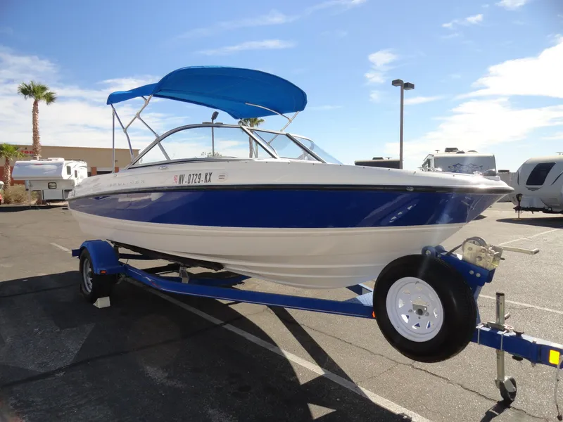 Slide: The Image of 2006 Bayliner 195 Bowrider boat on trailer with blue canopy in sunny parking lot. - 4