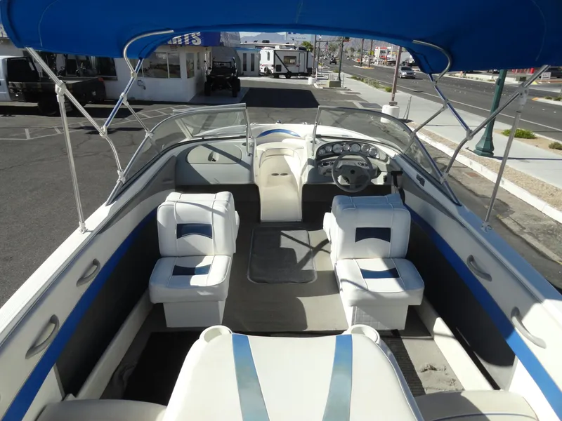 Slide: The Image of 2006 Bayliner 195 Bowrider with blue canopy and white seating, parked on street. - 6