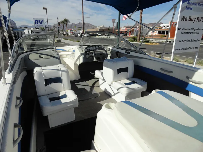 Slide: The Image of 2006 Bayliner 195 Bowrider interior with white seating and dashboard, parked outdoors. - 7