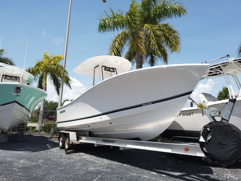 The Image of 2025 Regulator 25 boat on trailer, parked outdoors near palm trees. - 0