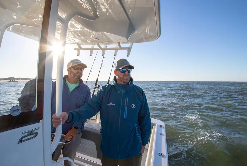 Slide: The Image of Two men on a 2025 Regulator 25 boat enjoying a sunny day at sea. - 12