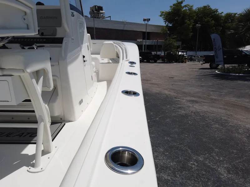 Slide: The Image of 2025 Regulator 25 boat deck with rod holders, parked outdoors. - 22