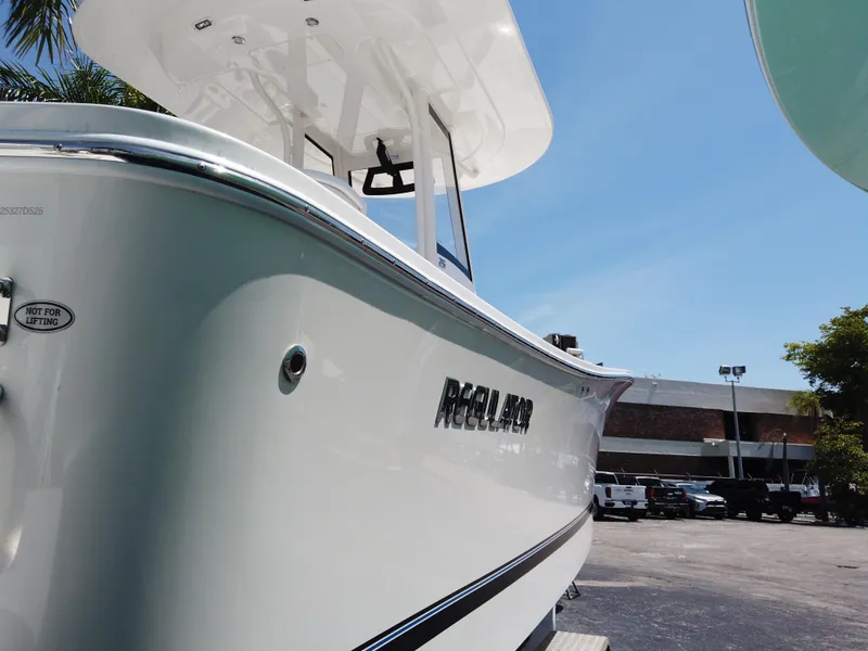 Slide: The Image of 2025 Regulator 25 boat, sleek white design, parked outdoors under clear blue sky. - 23