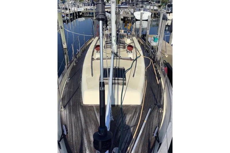 Slide: The Image of 1984 Young Sun 35 sailboat deck view at marina, showcasing rigging and wooden details. - 5