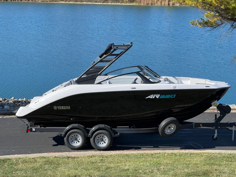 Slide: The Image of 2025 Yamaha AR220 boat on trailer by a lake. - 1