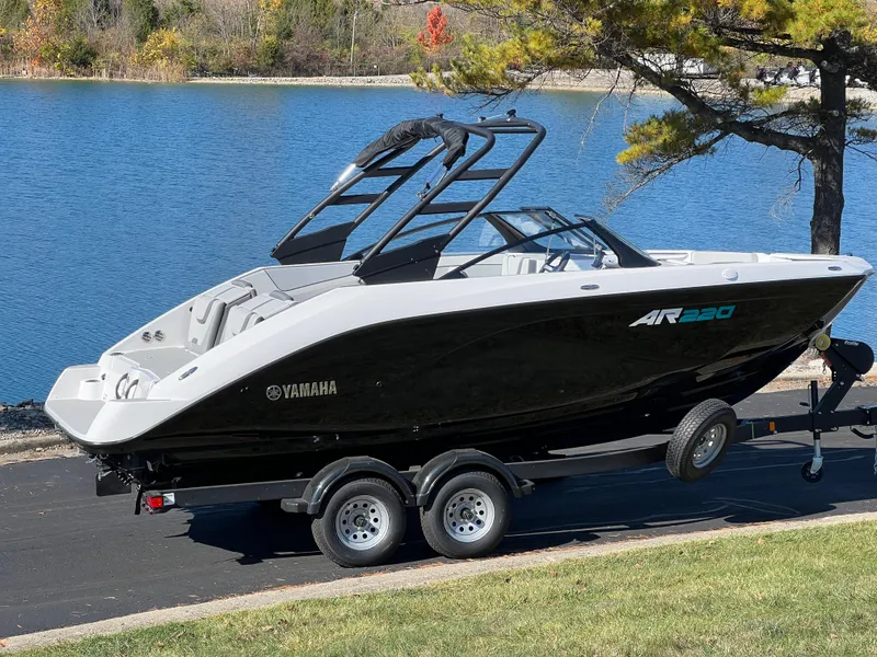 Slide: The Image of 2025 Yamaha AR220 boat on trailer by a lake. - 2