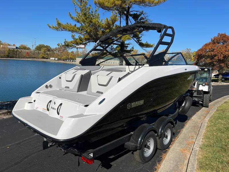 Slide: The Image of 2025 Yamaha Boats AR220 on trailer by a lake, sleek design, black and white exterior. - 5
