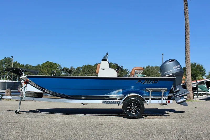 Slide: The Image of 2025 Avid 18 Rogue CC boat on trailer, blue exterior, parked outdoors. - 1