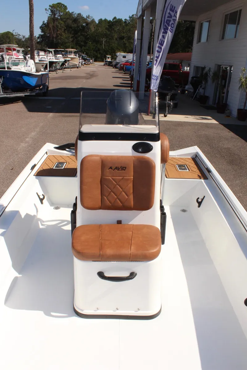 Slide: The Image of 2025 Avid 18 Rogue CC boat with tan seating, docked outdoors. - 19