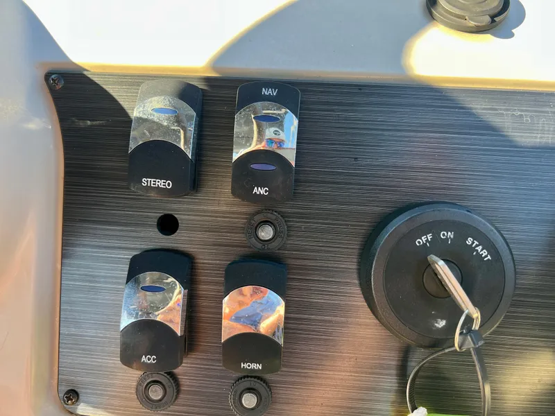 Slide: The Image of Control panel of 2023 Cypress Cay Seabreeze 232 boat with switches and ignition key. - 16
