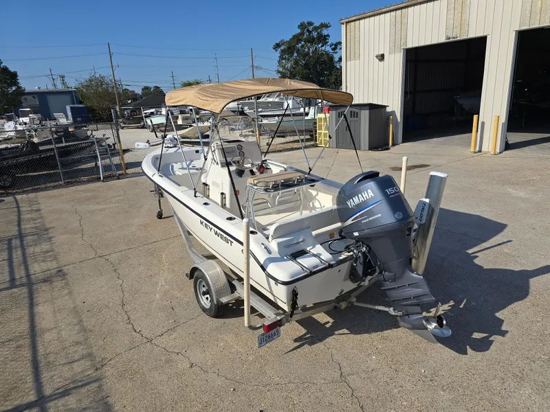 Slide: The Image of 2012 Key West 189 FS boat with Yamaha motor, parked outdoors near a warehouse. - 7