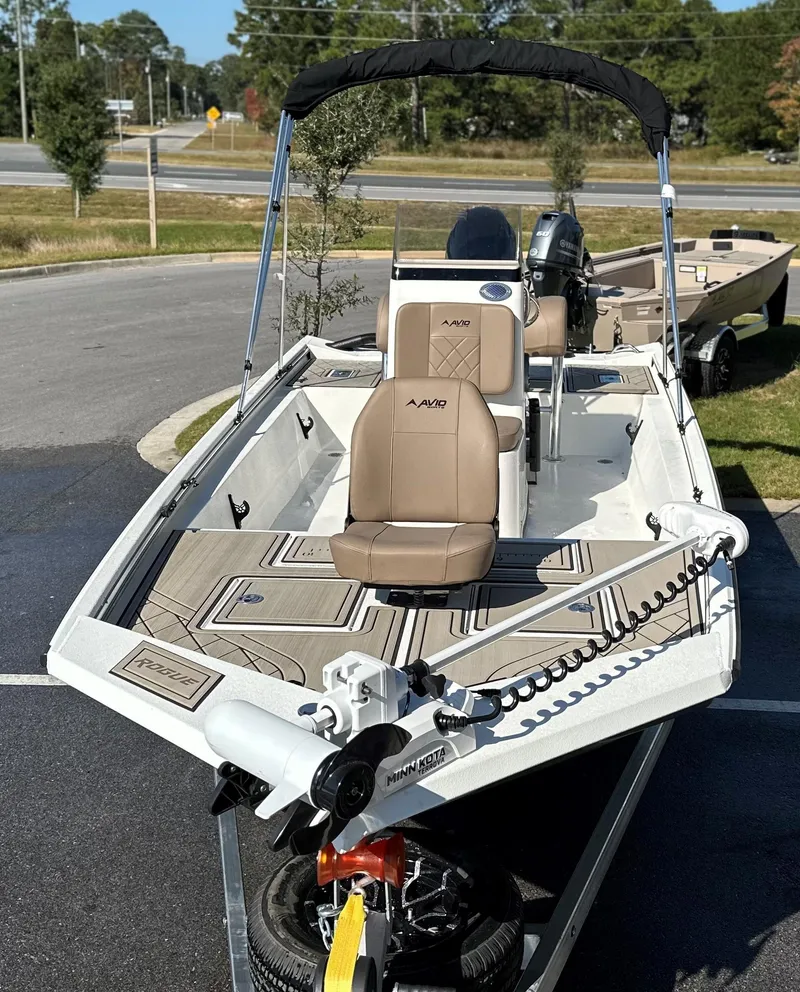 Slide: The Image of 2025 Avid 18 Rogue boat with seating and motor, parked outdoors. - 17