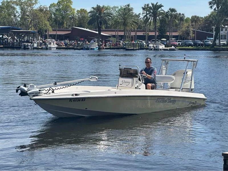 Slide: The Image of 2005 Young Boats 20 on a calm river with palm trees in the background. - 0