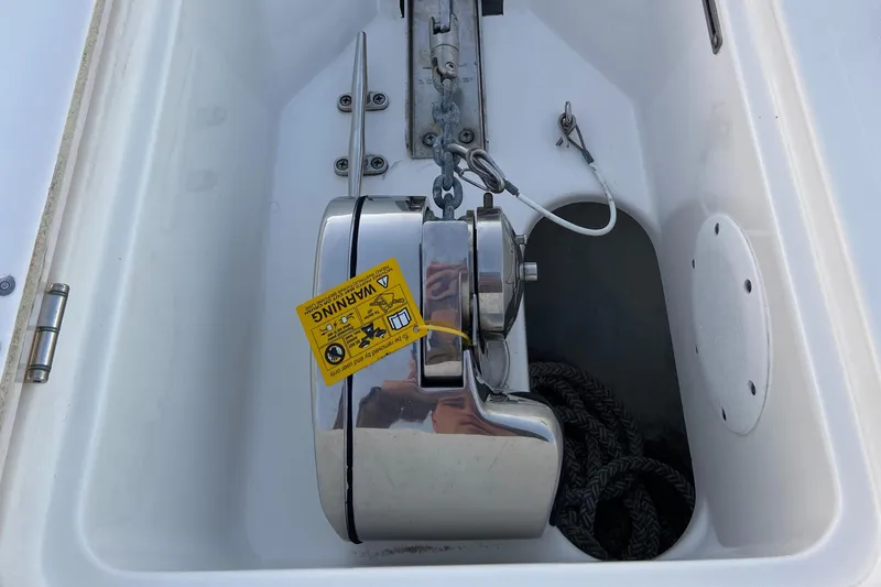 Slide: The Image of Anchor compartment of 2022 Tidewater 232 LXF boat with stainless steel anchor and warning label. - 11