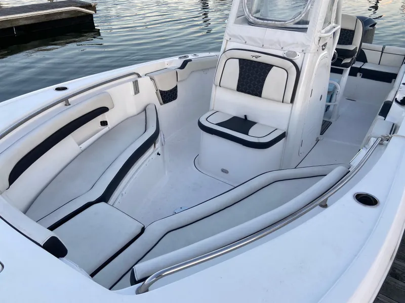 Slide: The Image of 2022 Tidewater 232 LXF boat interior with white seating and console, docked on calm water. - 3