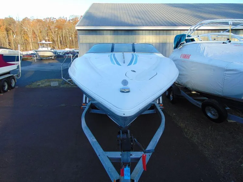 Slide: The Image of 1995 Baja 272 boat on trailer, parked outdoors near other boats. - 2